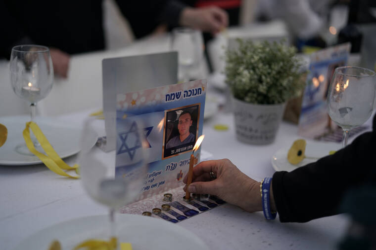 LEO CORREA / AP
A person lights a candle on a table set for hostages being held in the Gaza Strip by the Hamas militant group during the Jewish holiday of Hanukkah in the Hostages Square at the Museum of Art, in Tel Aviv, Israel, Friday, Dec. 8.
