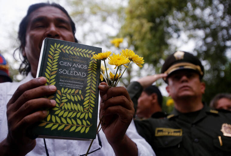 JOHN VIZCAINO /REUTERS
A resident holding flowers and a book Cien Anos de Soledad (One Hundred Years of Solitude) by Colombian Nobel laureate Gabriel Garcia Marquez takes part in a symbolic public funeral for Garcia Marquez, in Aracataca April 21, 2014.