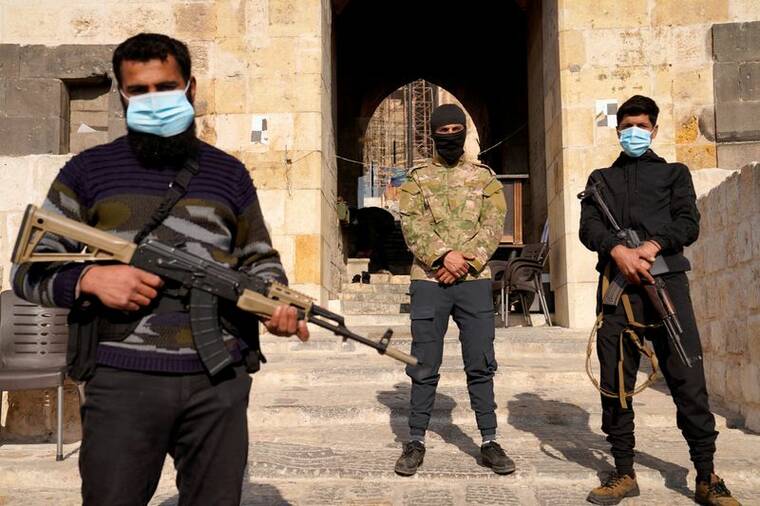KARAM al-MASRI / REUTERS
Rebel fighters holds weapons Monday at the Citadel of Aleppo, in Aleppo, Syria, after rebels ousted President Bashar al-Assad over the weekend, ending a 13-year civil war.